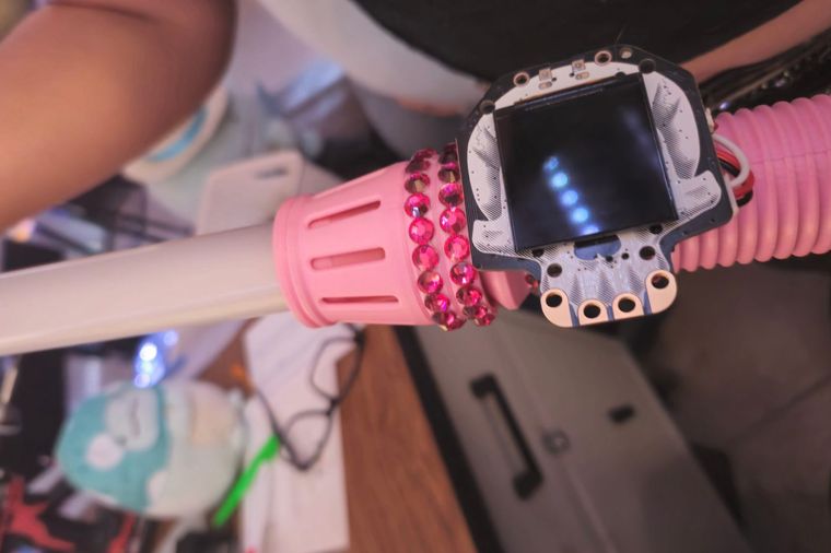 A 3D-printed lightsaber hilt set with rhinestones, a board and screen at the emitter, and a lit blade