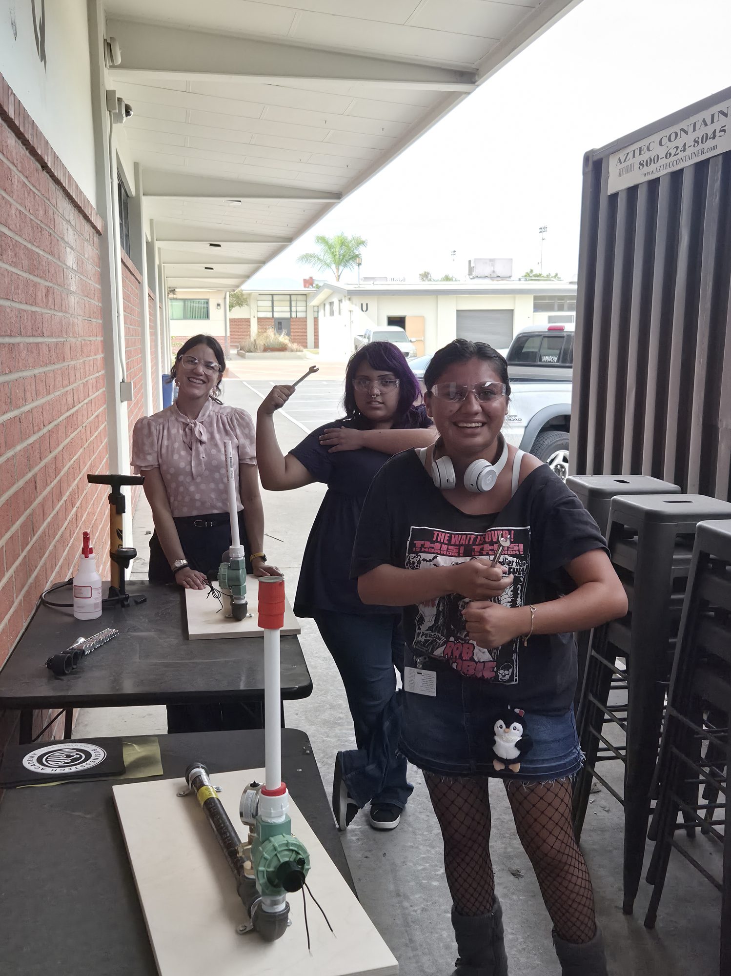 Two students posing beside the pneumatic launcher they built