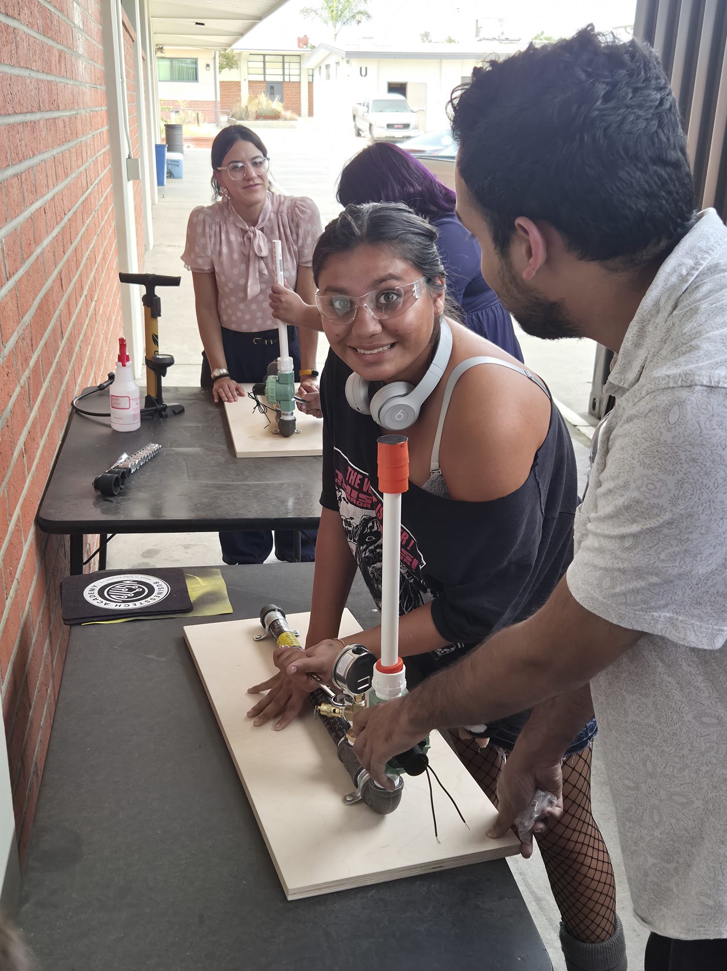 A student driving fasteners into the launch platform with a Collins Aerospace engineer alongside